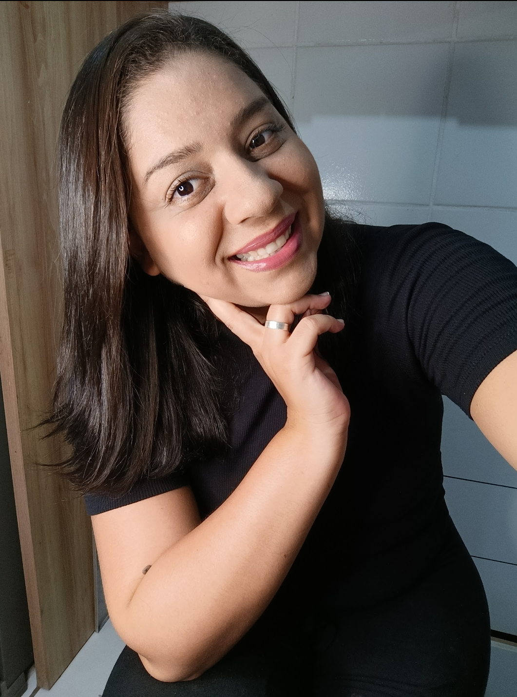 Suzi sorrindo, com a mão apoiada no rosto.